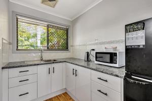 a kitchen with white cabinets and a microwave at Sanctuary Lakes Fauna Retreat in Hervey Bay
