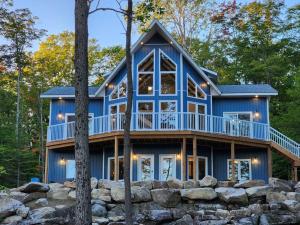 a blue house with a wrap around deck at Luxury Waterfront Cottage on Little Doe Lake in Burks Falls