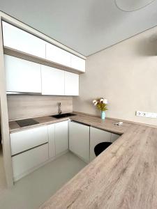 a kitchen with white cabinets and a wooden counter at Апарт-отель напротив ботанического сада in Astana