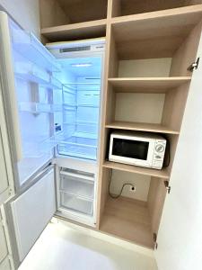 a refrigerator with its door open with a microwave at Апарт-отель напротив ботанического сада in Astana