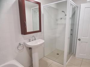 a white bathroom with a sink and a shower at Moore Park Apartments in Armidale