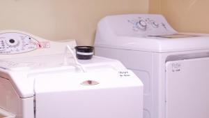 two white washing machines and a sink in a room at Entire Cozy Basement Studio in Winnipeg South Transcona in Winnipeg