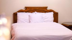 a bed with a wooden headboard with white sheets and pillows at Entire Cozy Basement Studio in Winnipeg South Transcona in Winnipeg
