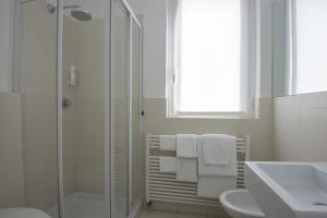 a white bathroom with a shower and a sink at Hotel Serenella in Baveno
