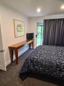 a bedroom with a bed and a desk with a television at Moore Park Apartments in Armidale