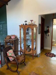 a room with a wooden cabinet and a chair at Casa Especial em Catas Altas in Catas Altas