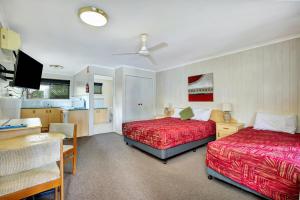 a bedroom with two beds and a table and a kitchen at Sanctuary Lakes Fauna Retreat in Hervey Bay