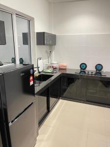 uma cozinha com um frigorífico preto e uma bancada em Anna 温馨住家住宅 em Sibu