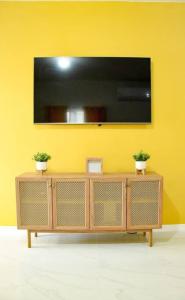Telewizor na żółtej ścianie z dwoma doniczkami w obiekcie Lemonade (With breakfast Option, Beach Access) w Negril