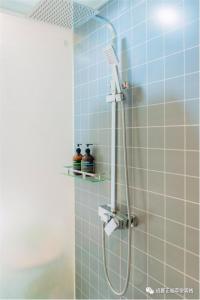 a shower in a bathroom with blue tiles at Chengdu Zhengfu Cao Tang Inn in Chengdu