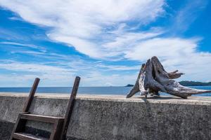 a pair of chairs sitting on a wall next to the ocean at Haryugetu Guesthouse in NASA in Kaiyo