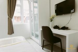 a bedroom with a desk with a chair and a tv at Flower Hill in Da Lat