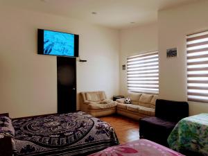 sala de estar con cama y TV de pantalla plana en Quinta Residencial El Colibrí en San Martín de las Pirámides
