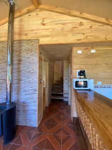 a kitchen with wooden walls and a counter with a microwave at CABAÑAS RUCA MALAL in Futrono