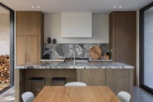 a kitchen with a wooden table and white cabinets at Low house Matakana in Matakana