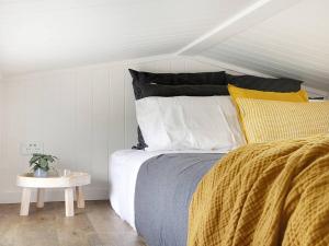a bedroom with a bed with yellow and white pillows at Yamba Tiny House Iris in Palmers Island