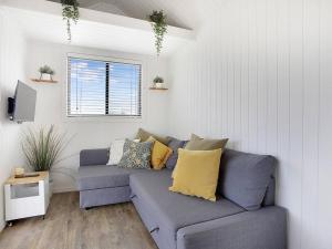 a living room with a blue couch and a window at Yamba Tiny House Iris in Palmers Island