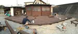 a man working on a wooden deck in front of a building at Haryugetu Guesthouse in NASA in Kaiyo