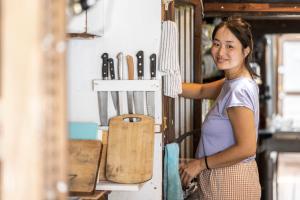a woman is standing next to a shelf with knives at Haryugetu Guesthouse in NASA in Kaiyo