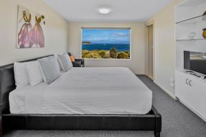 a bedroom with a large bed and a television at Manfield Seaside Bruny Island in Alonnah