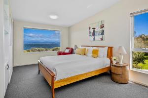 a bedroom with a bed and two windows at Manfield Seaside Bruny Island in Alonnah