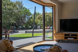 uma sala de estar com televisão e uma grande porta de vidro deslizante em Lumeah Retreat Bruny Island em Adventure Bay