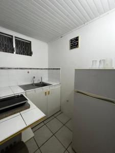 a white kitchen with a sink and a refrigerator at O Logis citron du Morne Jacob, Le Morne-Rouge Martinique in Le Morne Rouge