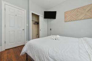 The Maverick - Luxurious Apartment - Free Parking - 2 Miles From Boston Logan Airport في تشيلسي: غرفة نوم بيضاء مع سرير أبيض وتلفزيون بشاشة مسطحة