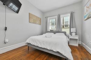 a white bedroom with a bed and a window at The Maverick Downstairs - Lux Apartment - Free Parking - 2 Miles From Airport & Downtown Boston in Chelsea