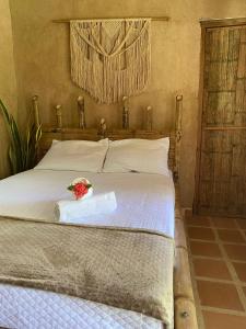a bedroom with a bed with a bouquet of flowers on it at Hostal Dos Quebradas in Santa Marta