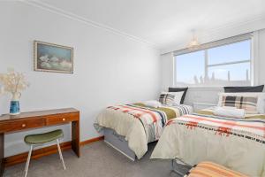 a bedroom with two beds and a desk and a window at #9 Dream in Rotorua