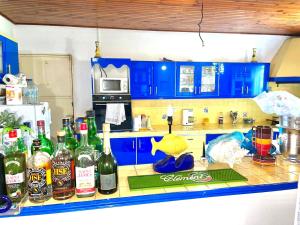 VILLA JASON في Ducos: مطبخ مع خزائن زرقاء وزجاجات من الكحول على منضدة