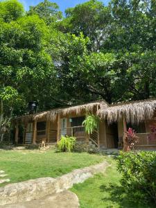 a house with a straw roof and a yard at Hostal Dos Quebradas in Santa Marta