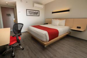 a hotel room with a bed and a desk and a chair at City Express by Marriott Santiago Aeropuerto in Santiago