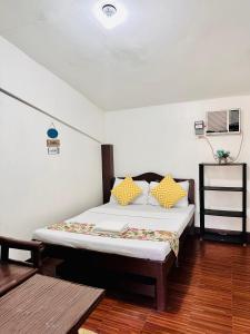 a bedroom with a bed with yellow pillows on it at Amancio's Balai - Near the Airport, City Center! in Puerto Princesa City