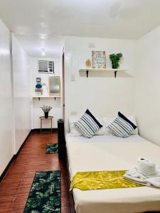 プエルト・プリンセサにあるAmancio's Balai - Near the Airport, City Center!のベッド2台とテーブルが備わる小さな客室です。