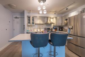 a kitchen with a island with two blue bar chairs at Mountain View One Bedroom Vacation Suite - WindTower 119 in Canmore