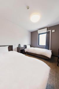 大阪市にあるOKINI HOTEL nambaのベッド2台と窓が備わるホテルルームです。