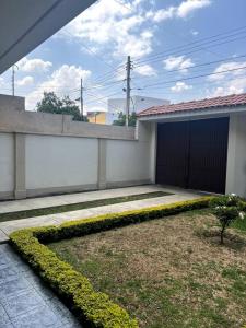 une maison blanche avec un garage et une usine dans l'établissement Acogedor Dpto. Con Jardin P.Baja, à Cochabamba