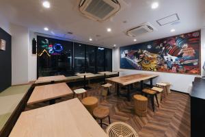 大阪市にあるOKINI HOTEL nambaの木製のテーブルと椅子、大きな壁画のあるレストラン