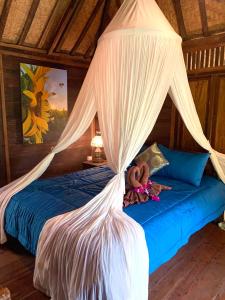 a bedroom with a bed with a mosquito net at Villa Kepuh in Singaraja