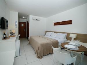 a hotel room with a bed and a table and chairs at Ap. Vista pra piscina - Iloa in Barra de São Miguel