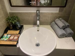 a white sink in a bathroom with a mirror and towels at Homestay Bắc Ninh in Bắc Ninh