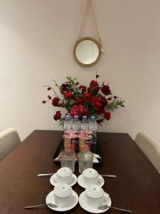 a table with plates and cups and a vase of flowers at Homestay Bắc Ninh in Bắc Ninh