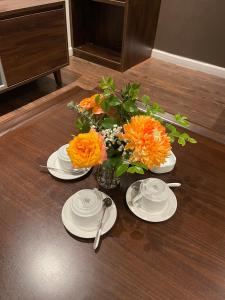 a table with plates and a vase of orange flowers at Homestay Bắc Ninh in Bắc Ninh