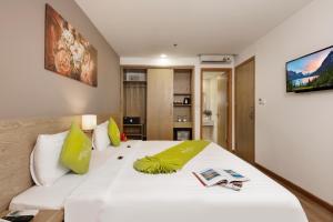 sypialnia z dużym białym łóżkiem z zielonymi poduszkami w obiekcie Ale Nha Trang Hotel w mieście Nha Trang