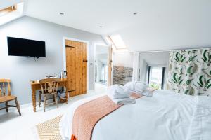 een slaapkamer met een bed, een televisie en een bureau bij Stone Barn in Skibbereen