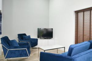 a living room with blue chairs and a tv at Green Lung Pool Villas Bangkok in Bang Krasop