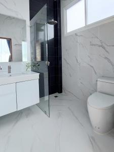 a white bathroom with a toilet and a glass shower at Green Lung Pool Villas Bangkok in Bang Krasop