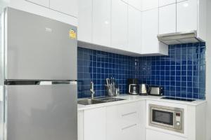 a kitchen with white cabinets and a stainless steel refrigerator at Green Lung Pool Villas Bangkok in Bang Krasop
